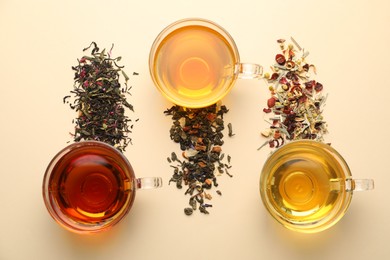 Photo of Different freshly brewed teas and dry leaves on beige background, flat lay