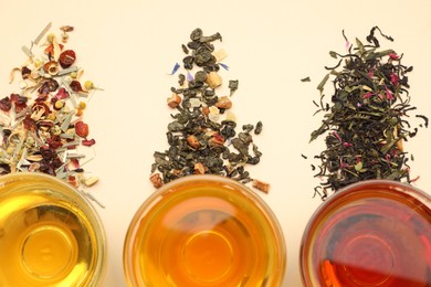 Photo of Different freshly brewed teas and dry leaves on beige background, flat lay