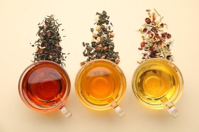 Photo of Different freshly brewed teas and dry leaves on beige background, flat lay