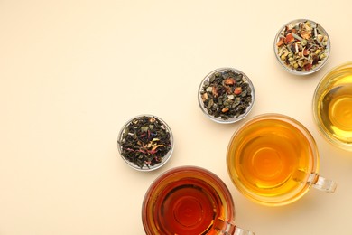 Photo of Different freshly brewed teas and dry leaves on beige background, flat lay. Space for text