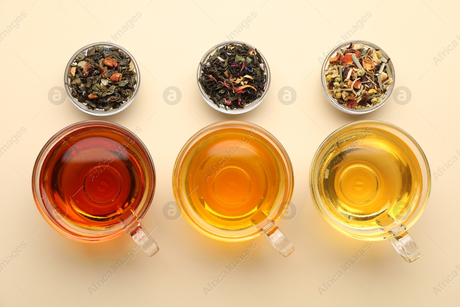 Different freshly brewed teas and dry leaves on beige background, flat lay Photo of Different freshly brewed teas and dry leaves on beige background, flat lay