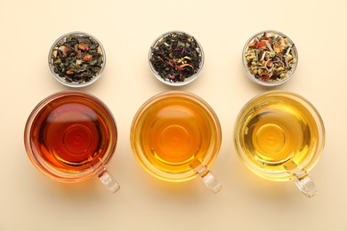 Photo of Different freshly brewed teas and dry leaves on beige background, flat lay