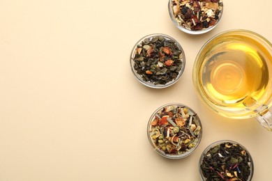 Photo of Delicious herbal tea in glass cup and dry leaves on beige background, flat lay. Space for text