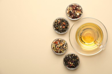 Photo of Delicious herbal tea in glass cup and dry leaves on beige background, flat lay. Space for text