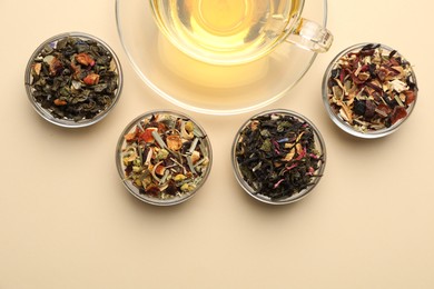 Photo of Delicious herbal tea in glass cup and dry leaves on beige background, flat lay