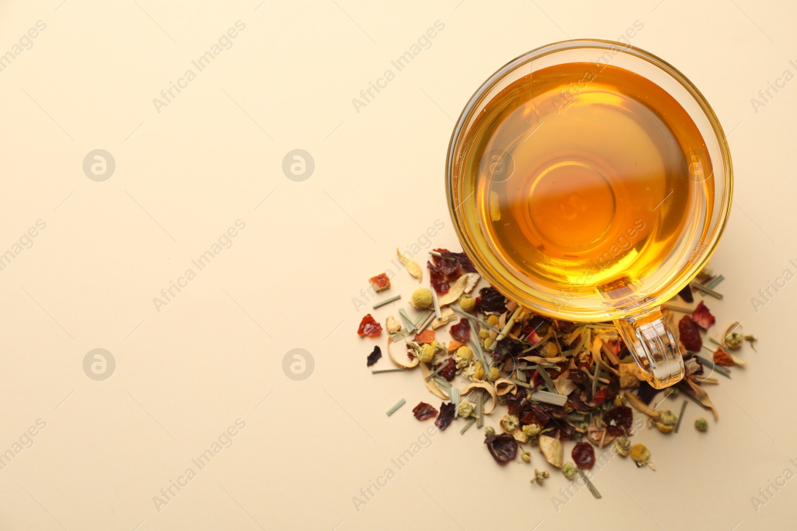 Delicious herbal tea in glass cup and dry leaves on beige background, flat lay. Space for text Photo of Delicious herbal tea in glass cup and dry leaves on beige background, flat lay. Space for text