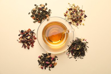 Photo of Delicious herbal tea in glass cup and dry leaves on beige background, flat lay