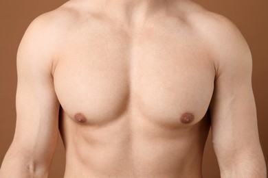 Photo of Young man with smooth chest after epilation procedure on brown background, closeup