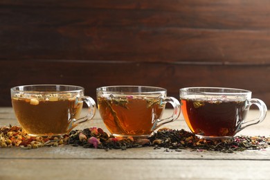 Photo of Different herbal teas and dry leaves on wooden table. Space for text