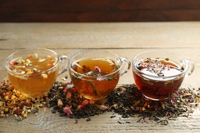 Photo of Different herbal teas and dry leaves on wooden table