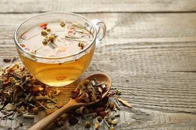 Photo of Delicious herbal tea and dry leaves on wooden table, closeup. Space for text