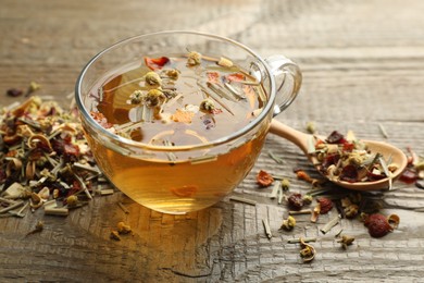 Photo of Delicious herbal tea and dry leaves on wooden table, closeup