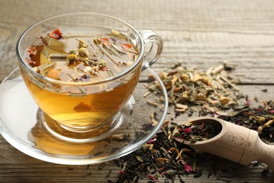 Photo of Delicious herbal tea and dry leaves on wooden table, closeup