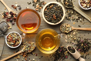 Photo of Different herbal teas and dry leaves on wooden table, flat lay