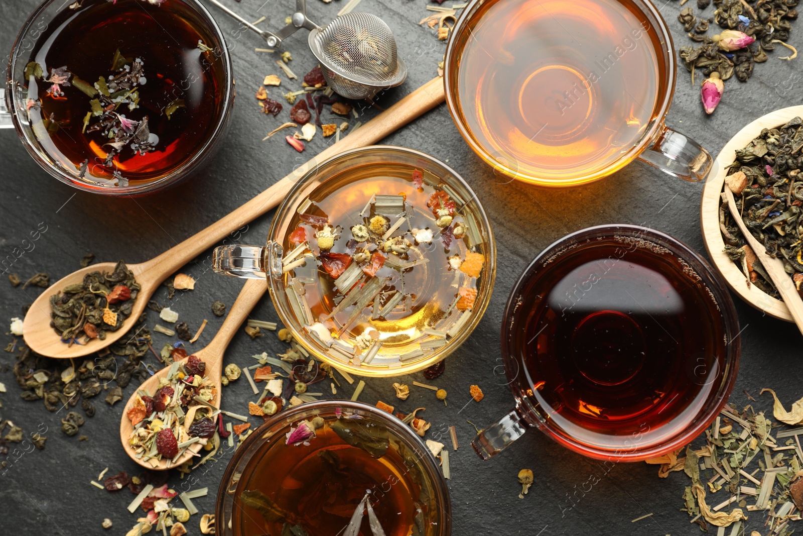 Different herbal teas and dry leaves on black table, flat lay Photo of Different herbal teas and dry leaves on black table, flat lay