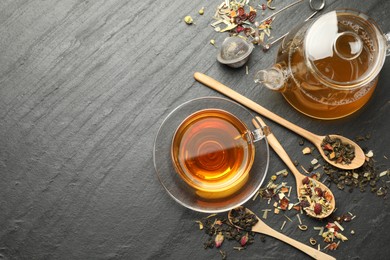 Photo of Delicious herbal tea and dry leaves on black table, flat lay. Space for text