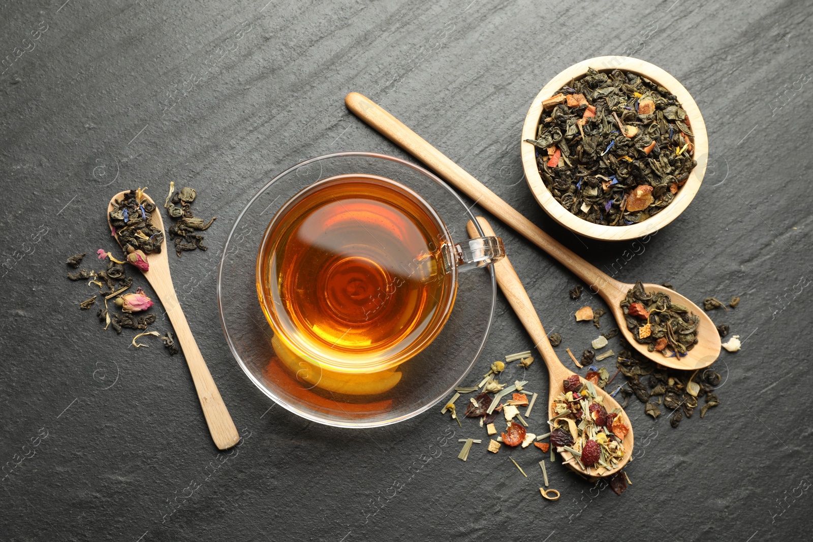 Delicious herbal tea and dry leaves on black table, flat lay Photo of Delicious herbal tea and dry leaves on black table, flat lay