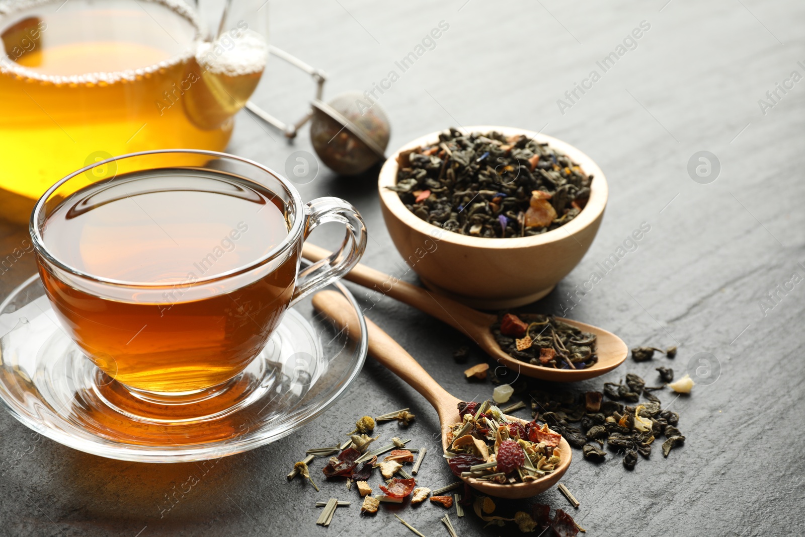 Delicious herbal tea and dry leaves on black table, closeup Photo of Delicious herbal tea and dry leaves on black table, closeup