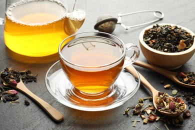 Photo of Delicious herbal tea and dry leaves on black table, closeup