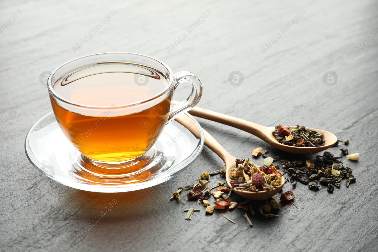 Delicious herbal tea and dry leaves on black table, closeup Photo of Delicious herbal tea and dry leaves on black table, closeup