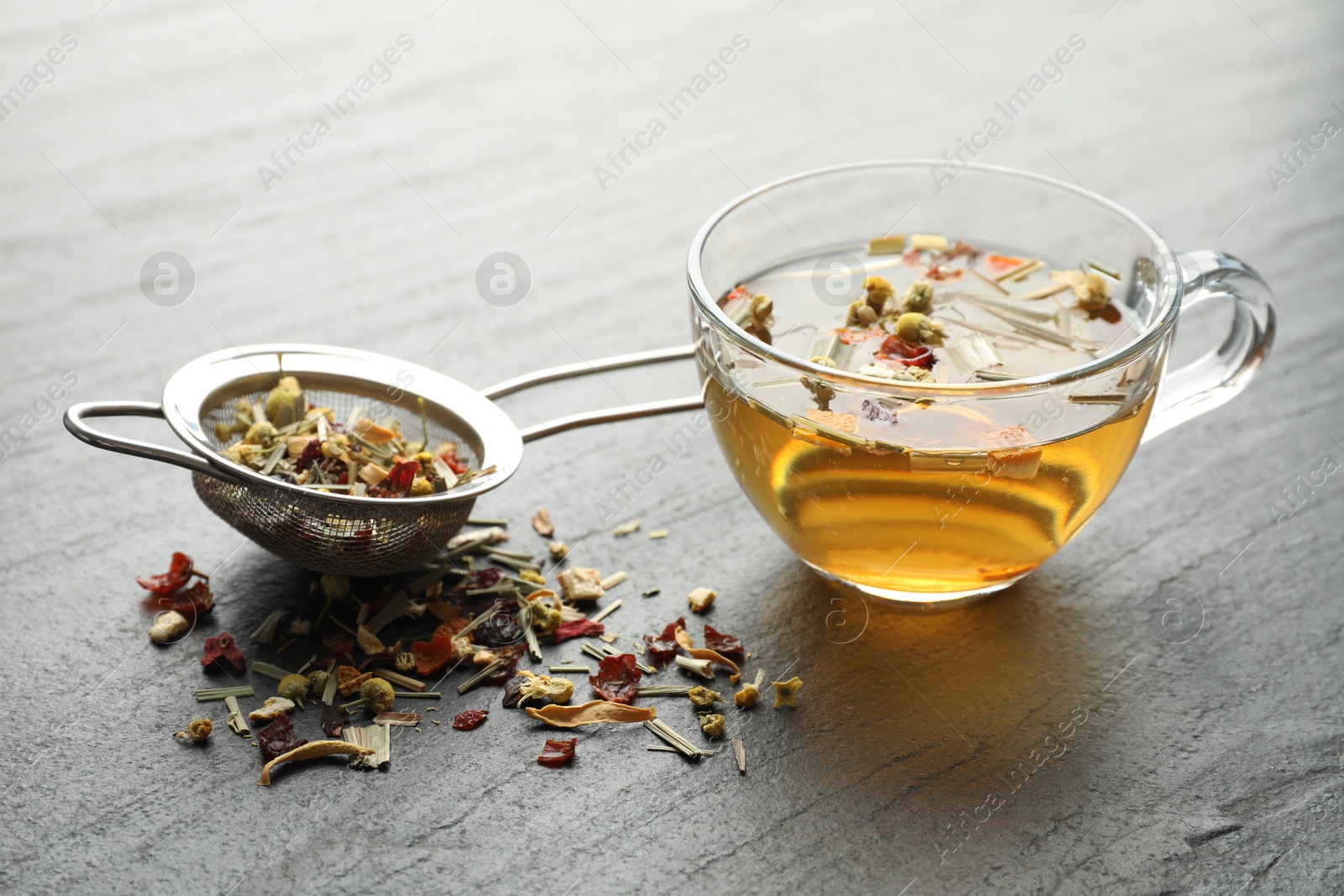 Delicious herbal tea and dry leaves on black table, closeup Photo of Delicious herbal tea and dry leaves on black table, closeup
