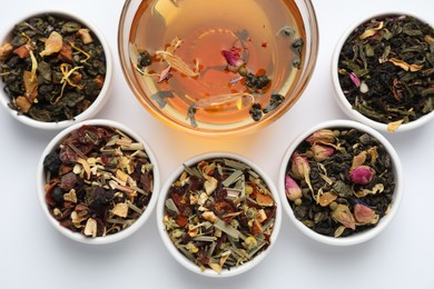 Photo of Delicious herbal tea and different brews on white background, flat lay