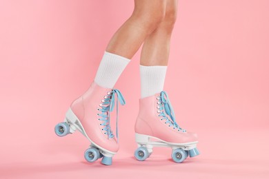 Photo of Woman in roller skates on pink background, closeup