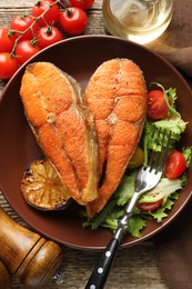 Photo of Seafood. Tasty salmon steaks served with salad and lemon on wooden table, flat lay