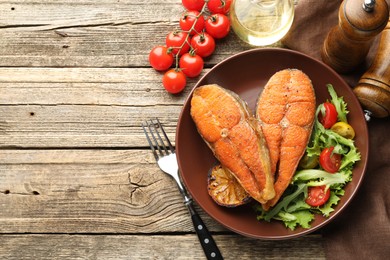 Photo of Seafood. Tasty salmon steaks served with salad and lemon on wooden table, flat lay. Space for text