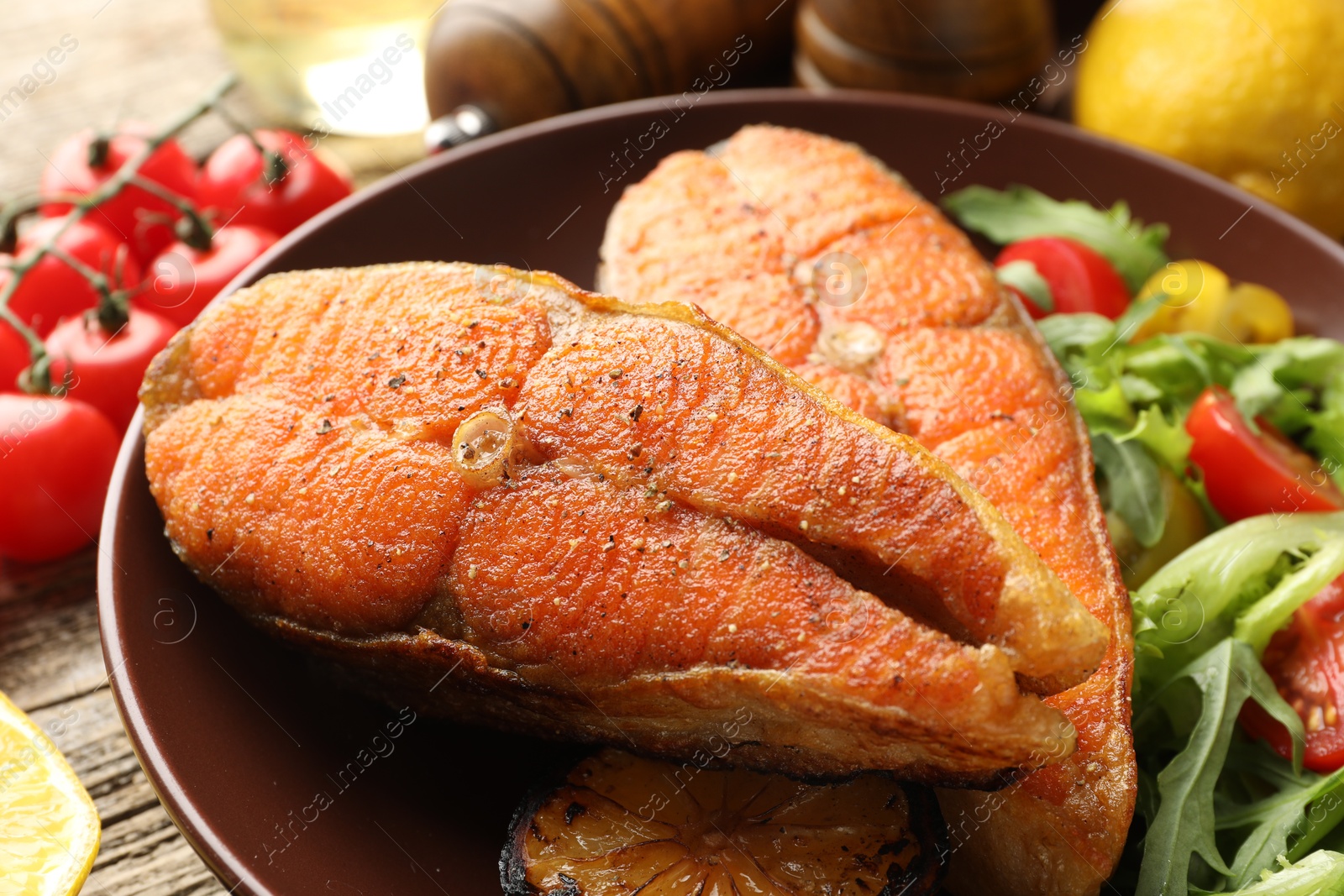 Seafood. Tasty salmon steaks served with salad on wooden table, closeup Photo of Seafood. Tasty salmon steaks served with salad on wooden table, closeup