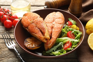 Photo of Seafood. Tasty salmon steaks served with salad and lemon on wooden table, closeup