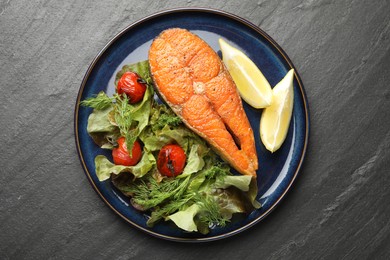 Photo of Seafood. Tasty salmon steak served with salad and lemon on black table, top view