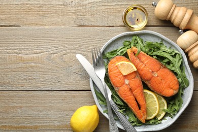 Photo of Seafood. Tasty salmon steaks served with arugula and lemon on wooden table, flat lay. Space for text
