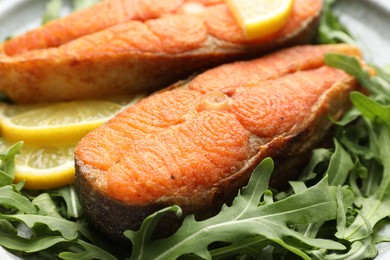 Photo of Seafood. Tasty salmon steaks, arugula and lemon on table, closeup