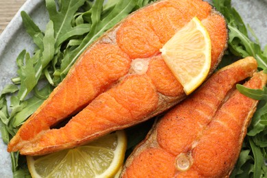 Photo of Seafood. Tasty salmon steaks, arugula and lemon on table, top view