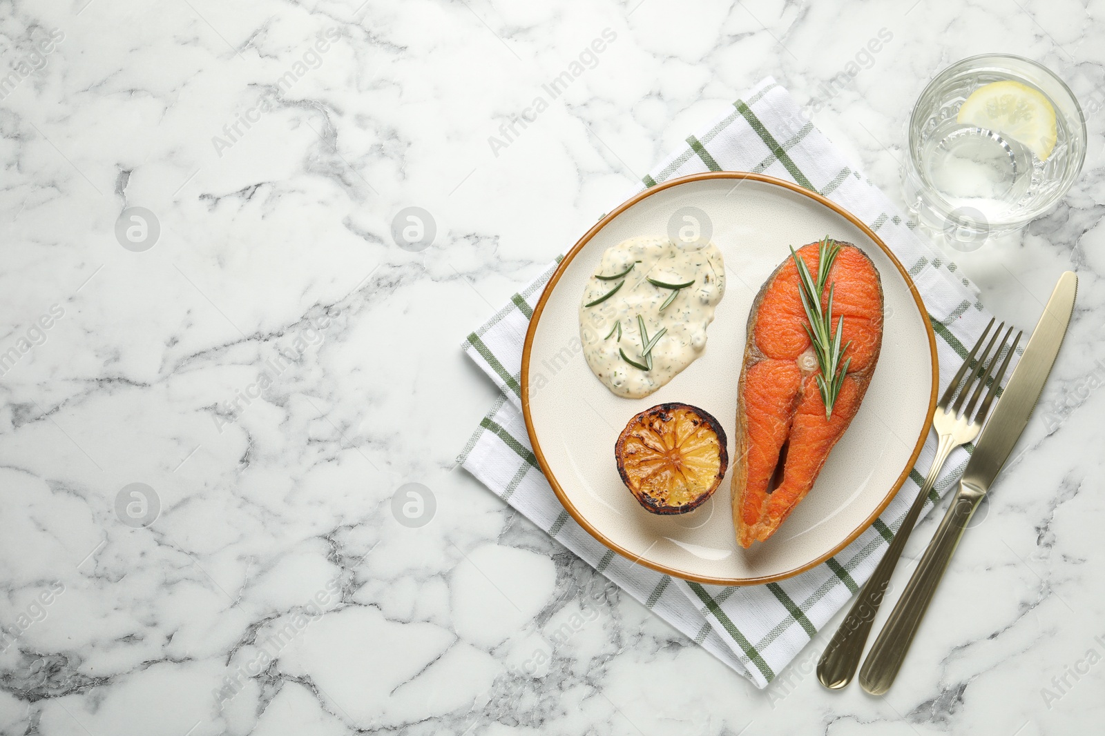 Seafood. Tasty salmon steak served with sauce, rosemary and lemon on white marble table, flat lay. Space for text Photo of Seafood. Tasty salmon steak served with sauce, rosemary and lemon on white marble table, flat lay. Space for text