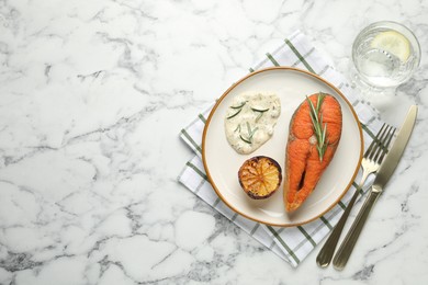 Photo of Seafood. Tasty salmon steak served with sauce, rosemary and lemon on white marble table, flat lay. Space for text