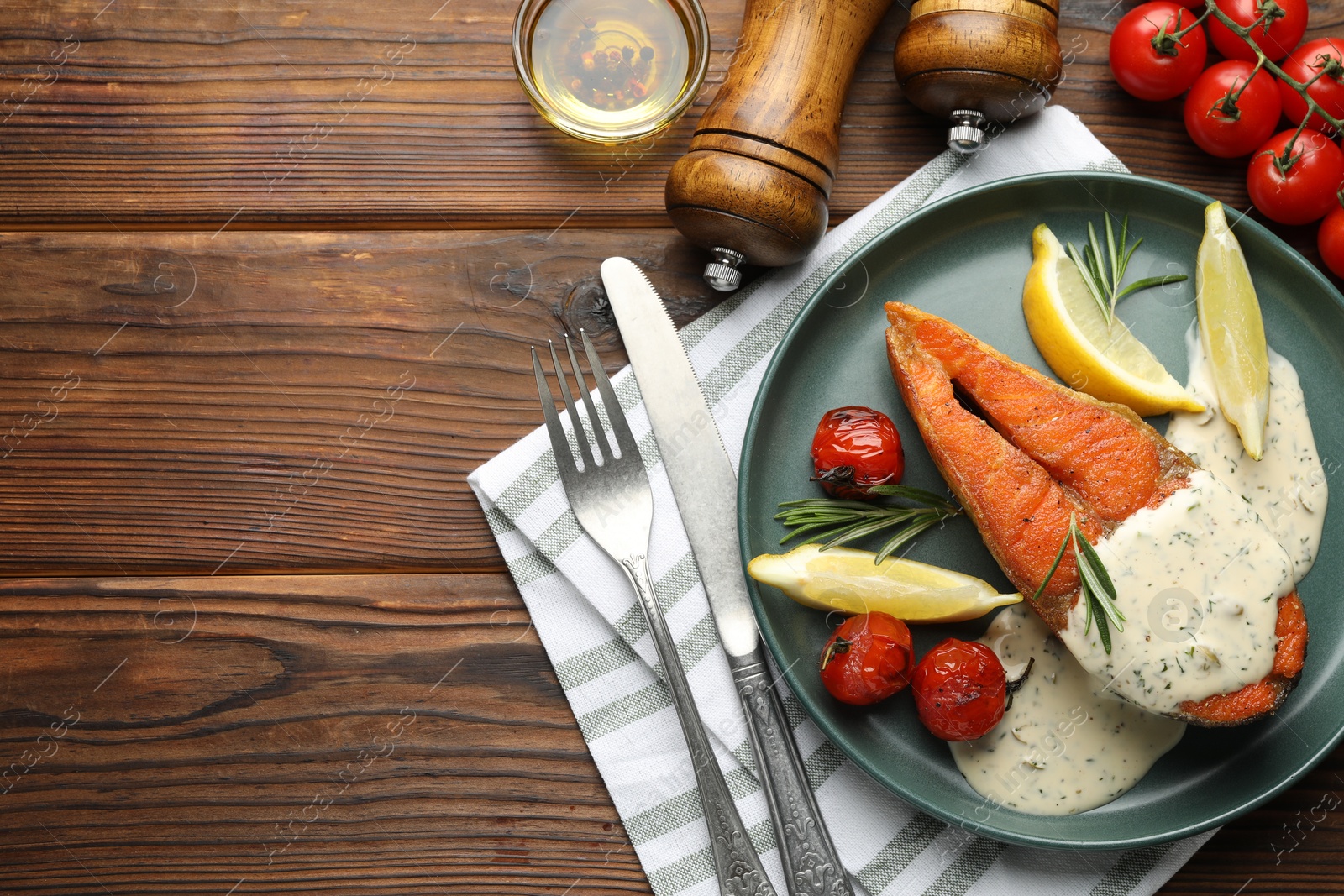Seafood. Tasty salmon steak served with sauce, tomatoes, rosemary and lemon on wooden table, flat lay. Space for text Photo of Seafood. Tasty salmon steak served with sauce, tomatoes, rosemary and lemon on wooden table, flat lay. Space for text