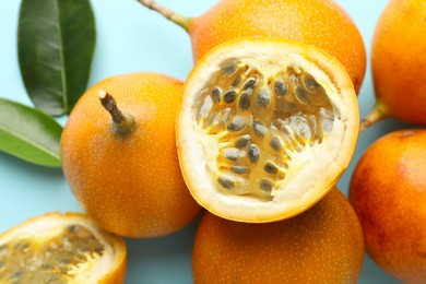 Photo of Ripe yellow passion fruits and leaves on light blue background, closeup