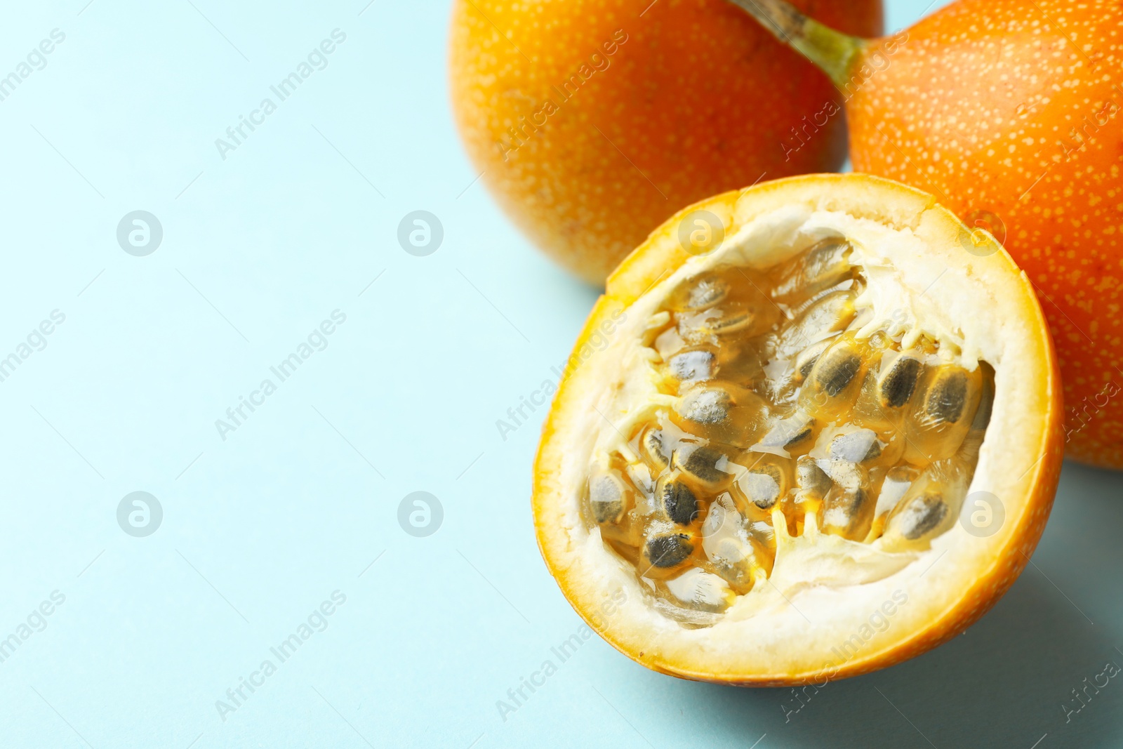 Ripe yellow passion fruits on light blue background, closeup. Space for text Photo of Ripe yellow passion fruits on light blue background, closeup. Space for text