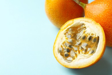 Photo of Ripe yellow passion fruits on light blue background, closeup. Space for text