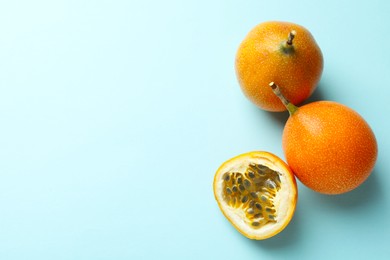 Photo of Ripe yellow passion fruits on light blue background, flat lay. Space for text