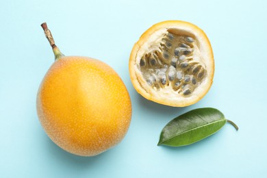 Photo of Ripe yellow passion fruits and leaf on light blue background, flat lay