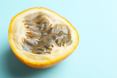 Photo of Piece of ripe yellow passion fruit on light blue background, closeup. Space for text