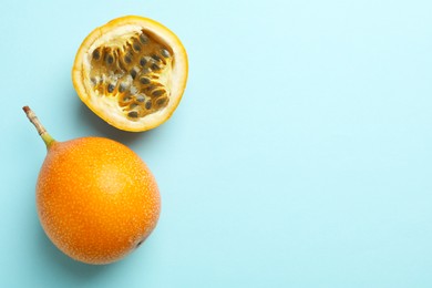 Photo of Ripe yellow passion fruits on light blue background, flat lay. Space for text