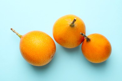 Photo of Ripe yellow passion fruits on light blue background, flat lay