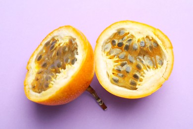 Photo of Pieces of ripe yellow passion fruit on lilac background, top view