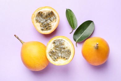 Photo of Ripe yellow passion fruits and leaves on lilac background, flat lay