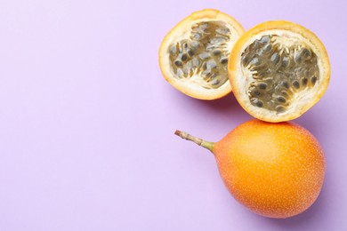 Photo of Ripe yellow passion fruits on lilac background, flat lay. Space for text