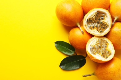 Photo of Ripe passion fruits and leaves on yellow background, flat lay. Space for text